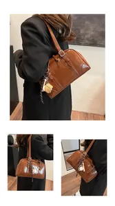 Close-up detail of stylish brown large capacity shoulder bag featuring a baseball charm