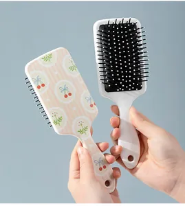 Detail view of a cute cartoon cherry print air cushion hairbrush for scalp massage