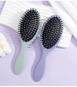 Detailed view of two Morandi color oval cushion hair brushes on purple background