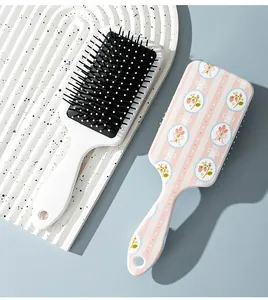 Detailed close-up showing the floral print and bristle side of two paddle hair brushes