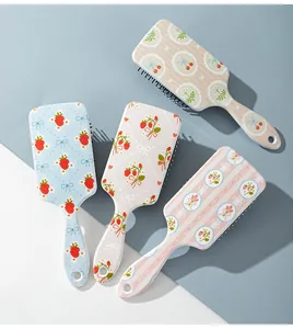 Detailed view of four cute paddle hairbrushes with colorful strawberry and floral prints.