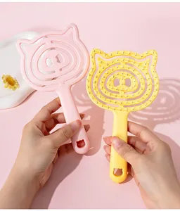 Close-up of cute pig-shaped hollow scalp massage combs in pink and yellow colors