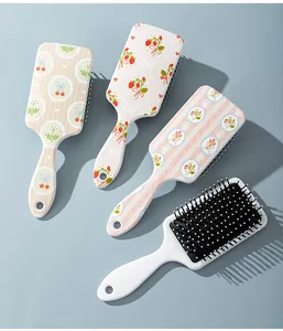 Close-up of cute cartoon fruit print hair massage paddle brushes on blue background