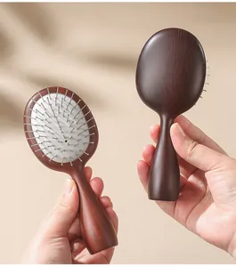 Detail view of portable hairbrush featuring wood grain finish and scalp massage steel pins.