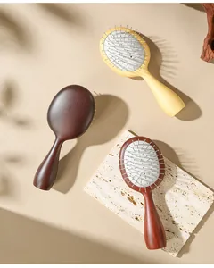 Detail view of wood grain scalp massage brushes with steel pins on a stone slab