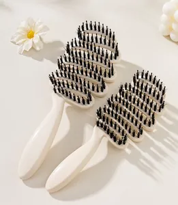 Detail view of two hollow boar bristle hairbrushes in cream white on a minimalist background