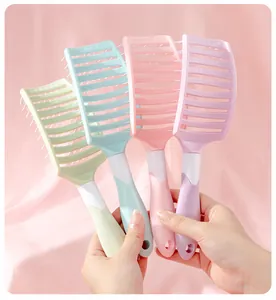 Close-up of four pastel-colored vented styling hairbrushes held in hands for volume