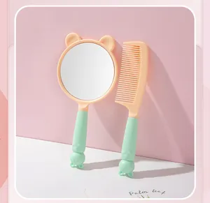 Detailed view of the cute cat-ear handheld mirror and matching comb set in pink and mint green