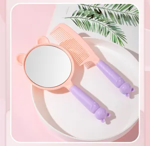Close-up of cute cat-themed pink and purple hand mirror and comb set in a white tray