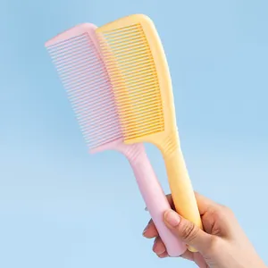 Mano sosteniendo peines para el cabello de plástico rosa y amarillo sobre fondo azul