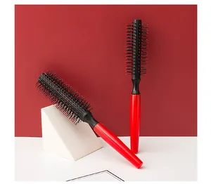 Detailed view of two red and black round hair styling brushes on a red background