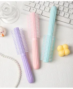 Close-up detail of three pastel macaron colored round curling hair brushes on a white desk.