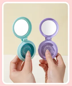 Close-up detail of the foldable pocket hairbrush with integrated mirror in pastel colors