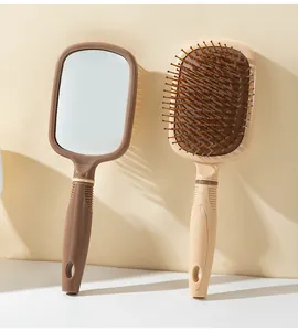Détail de la brosse à cheveux double fonction avec miroir intégré en beige et marron.