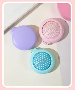 Macro view of portable circular folding hairbrushes with built-in mirrors in pastel colors.