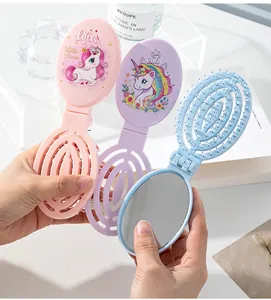 Close-up of portable folding hairbrush with mirror featuring cute unicorn prints