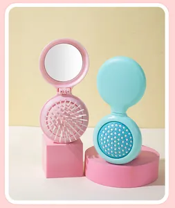 Close-up of portable foldable hairbrush with integrated mirror in pastel pink and teal colors