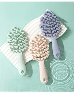 Three leaf-shaped scalp massager brushes in pastel colors displayed over water ripples.
