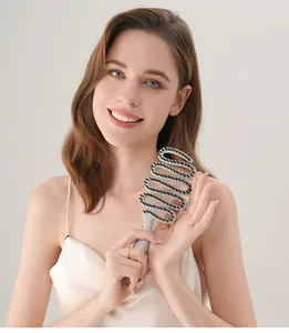 Detail view of a sandblasted ribbon-shaped hairbrush with boar bristles held by a model.