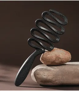 Close-up of a uniquely shaped sandblasted ribbon hairbrush resting on natural stones