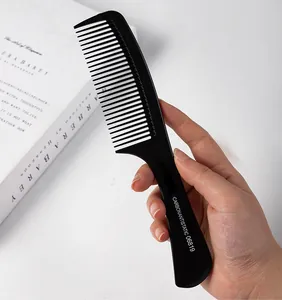 Close-up of a professional black carbon antistatic hairdressing comb held by hand