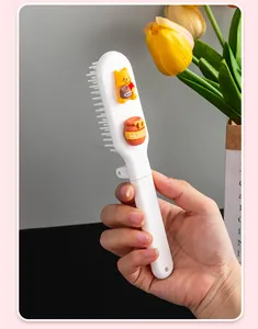 Detailed macro view of a portable 2-in-1 foldable hair brush featuring cute 3D cartoon bear charms