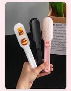Close-up of three foldable mini travel hairbrushes in white, black, and pink.