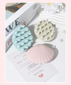 Shell-shaped silicone scalp massage brushes in soft pink, green, and blue pastel tones