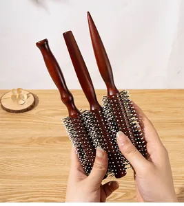 Detail view of three sizes of professional red-brown wooden round hair brushes for styling