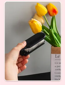 Macro view of a portable black foldable hair comb being held in a hand for scale