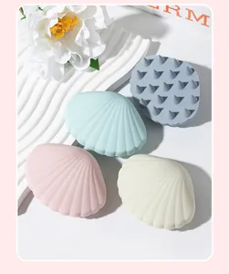 Four shell-shaped silicone scalp massage brushes in soft pastel pink, blue, and cream