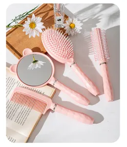Dettaglio di un set di 4 spazzole per capelli rosa con manici a trama diamantata e specchio