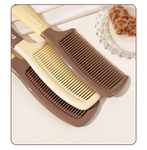 Vue détaillée des peignes à cheveux crème et marron avec motif Sleepy Cat sur le manche
