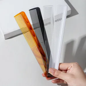 Hand holding a set of four fine-tooth plastic hair styling combs in diverse colors