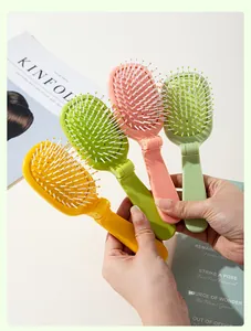 Handheld display of four colorful foldable cactus airbag hairbrushes for portable travel