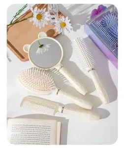 Primo piano di elegante set di 4 spazzole per capelli bianco crema con specchio