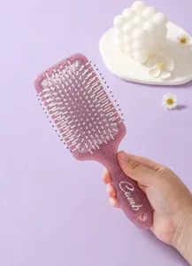 Close-up view of purple square paddle hairbrush with elegant totem prints on the handle