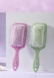 Macro view of purple and green air cushion hairbrushes featuring elegant white totem prints