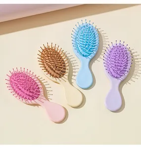 Four colorful pastel mini hairbrushes arranged on beige surface
