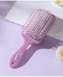 Close-up of a purple paddle hairbrush with elegant totem lace patterns on the handle