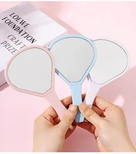 Primer plano de espejos de mano portátiles con forma de globo en colores pastel suave