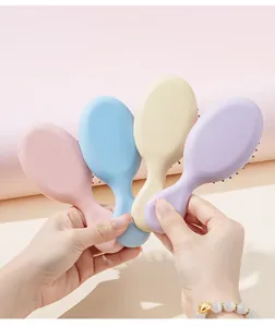 Close-up of cute mini hairbrushes in four pastel colors held in hands