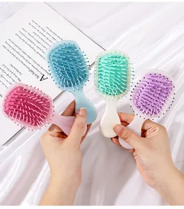 Close-up of four colorful mini air cushion hair brushes held in hands