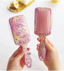 Detail of glitter paddle hairbrush with floral and butterfly patterns in pink and gold