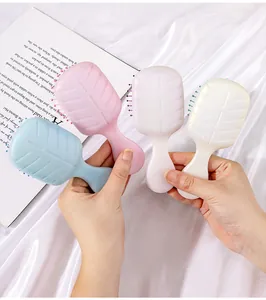 Four pastel colors of pearlescent mini cushion detangling hairbrushes held in hands