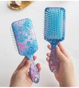Detailed view of two glitter printed square air cushion hairbrushes being held.