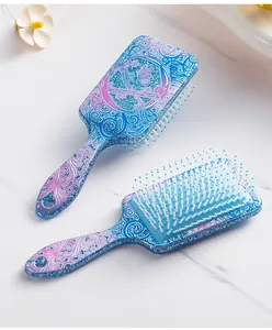 Detailed view of blue and purple glitter paddle brush with intricate butterfly prints.