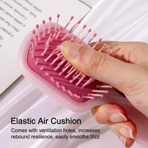 Pink mini cushion hairbrush held in hand on silk background