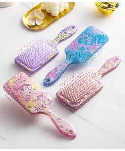 Detail view of four colorful glittery floral printed paddle hairbrushes on marble surface