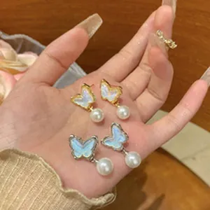 Gedetailleerde close-up van elegante vlinder oorbellen met parels in goud en zilver